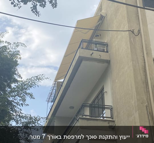 סוכך צהוב מותקן מעל מרפסת בקומה עליונה
